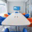Weißer Konferenztisch mit Stühlen in den Volksbankfarben: orange und blau